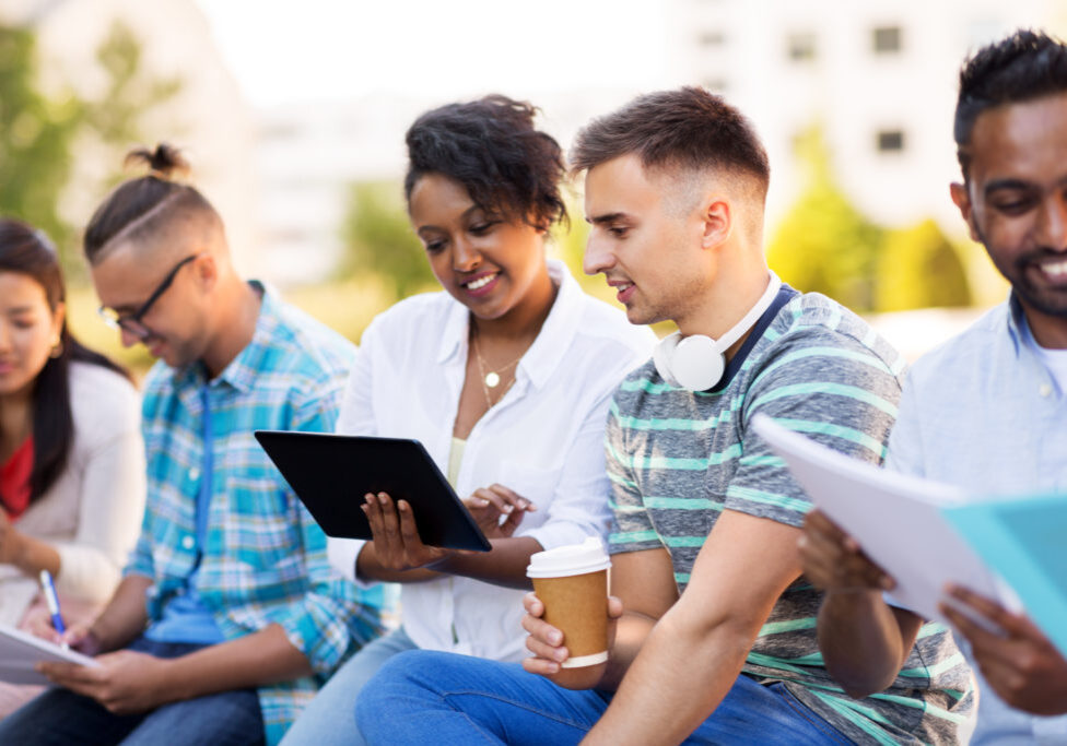 education, international and technology concept - group of happy exchange students with tablet pc computer and coffee outdoors